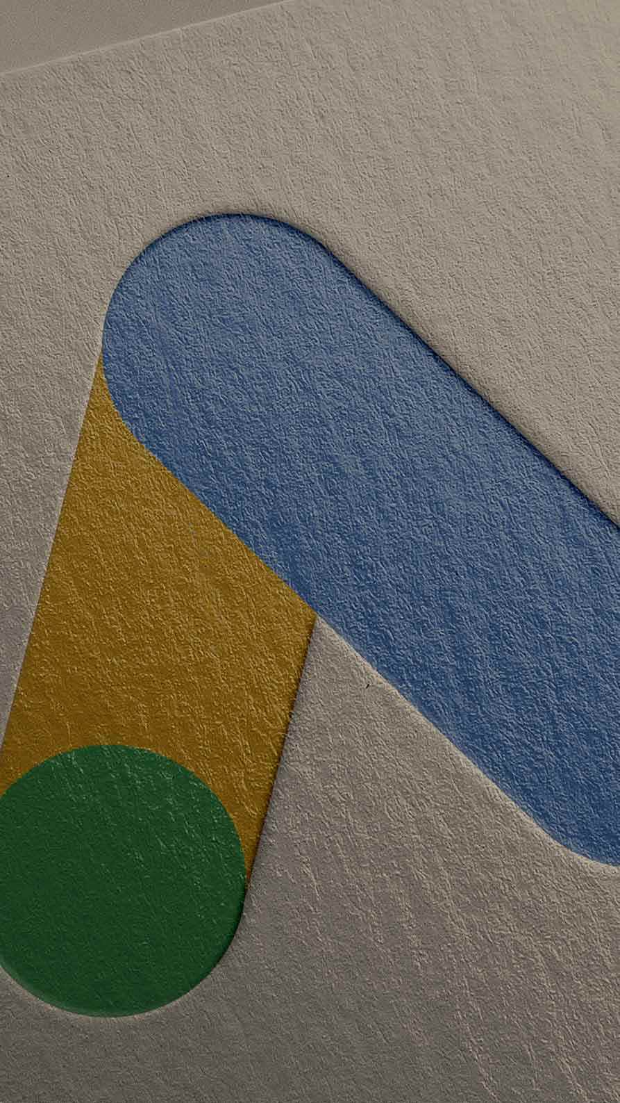A close up of the Google Ads logo embossed into high quality paper. The logo is a stylised capital letter A, in green, yellow and blue.