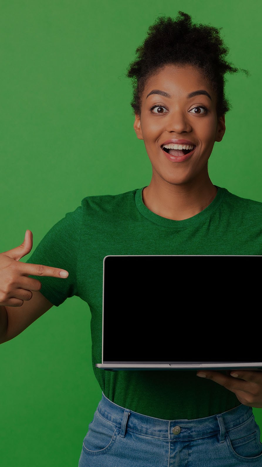 A photo of a woman smiling and pointing to a laptop enthusiastically. She's wearing a dark green T-shirt and there is a plain bright green background behind her. This photo is mildly suggestive that this article may be about websites, but it's all very figurative.